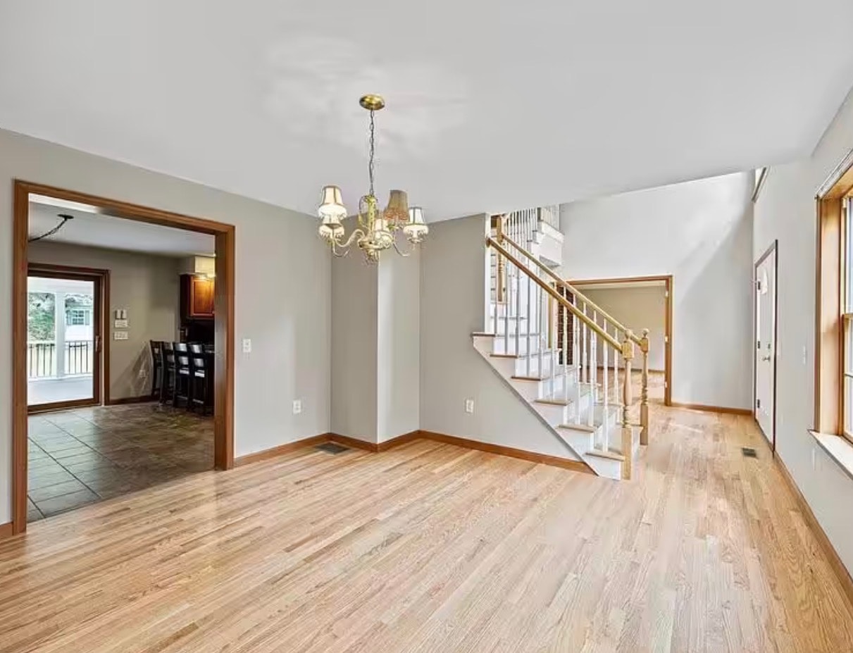 Refinished light oak hardwood floors in foyer with staircase and chandelier