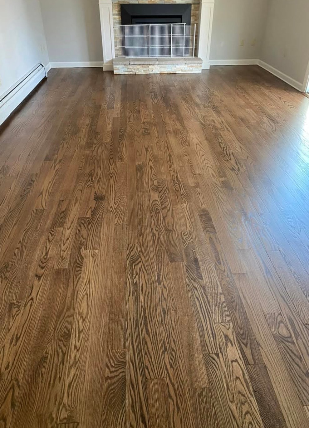 Dark stained hardwood floors with stone fireplace