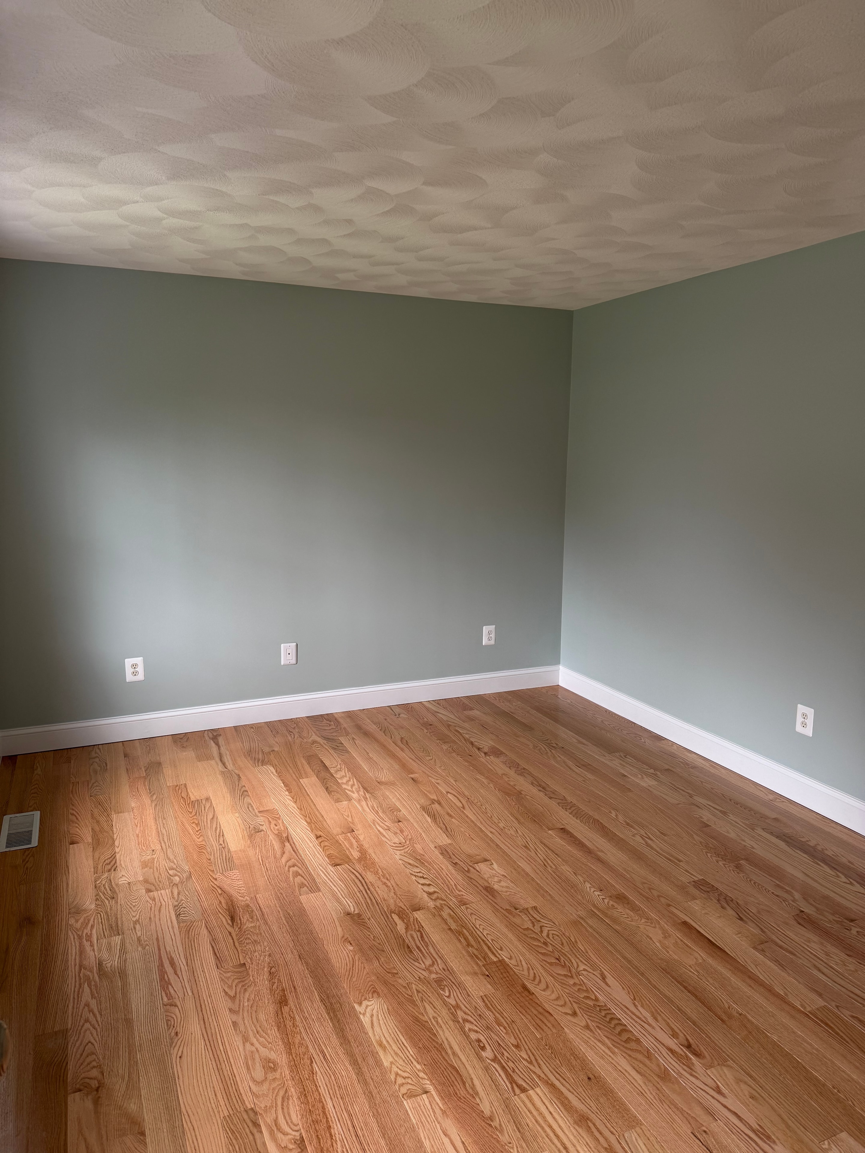 Sage green room with refinished hardwood floors