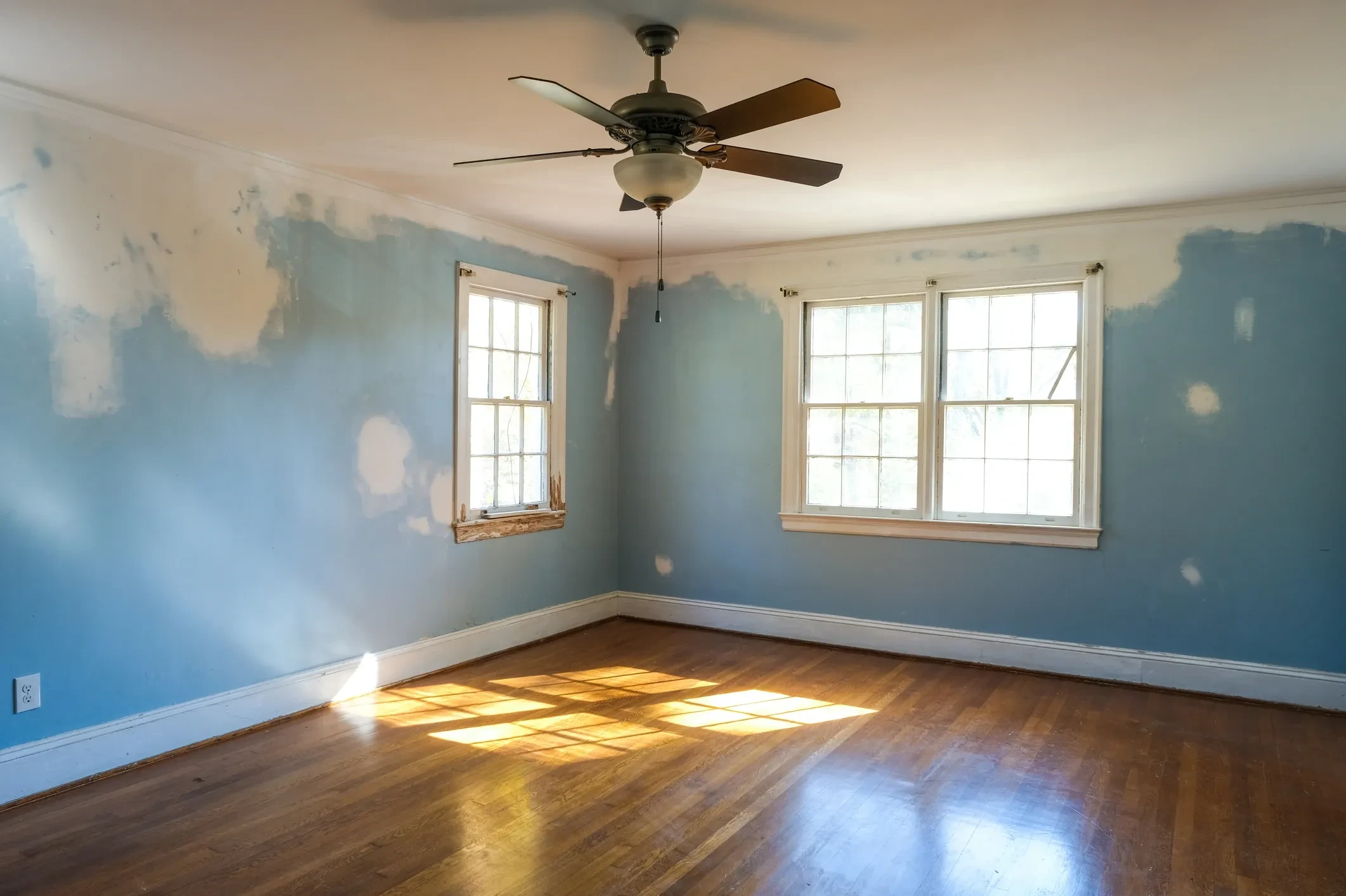 Empty room with freshly painted gray walls and refinished hardwood floors