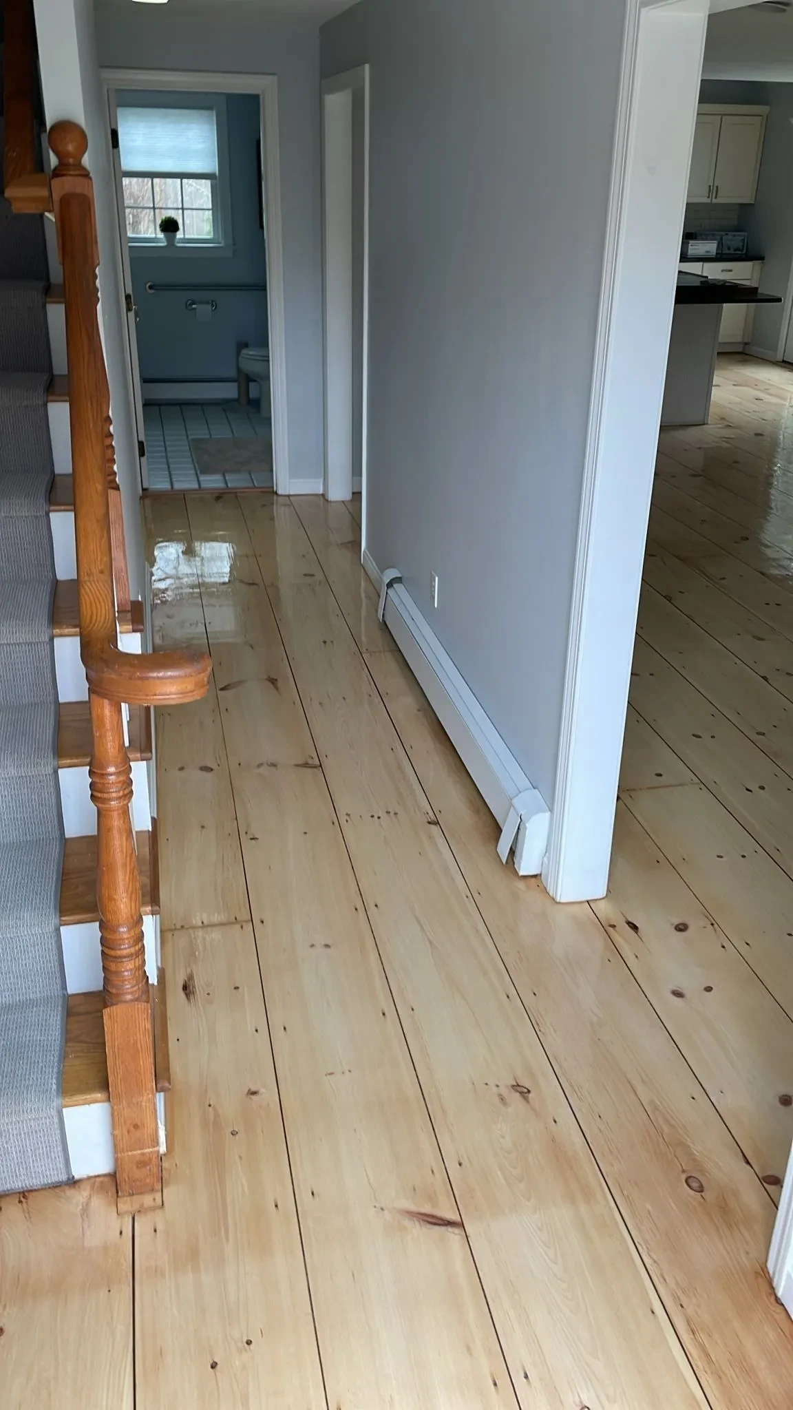 Refinished wide-plank pine floors in hallway with staircase